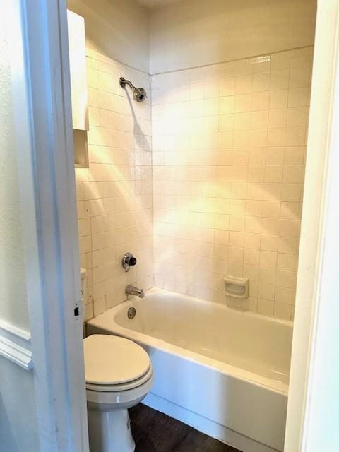 bathroom with hardwood / wood-style flooring, toilet, and tiled shower / bath combo