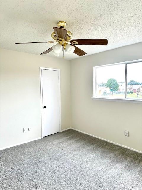 empty room with ceiling fan, carpet floors, and a textured ceiling