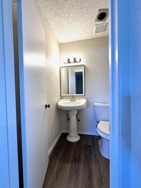 bathroom with toilet, hardwood / wood-style floors, and a textured ceiling