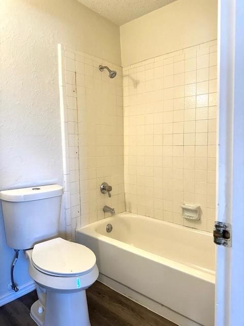 bathroom featuring tiled shower / bath combo, wood-type flooring, a textured ceiling, and toilet