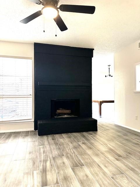 details with ceiling fan, a fireplace, hardwood / wood-style floors, and a textured ceiling