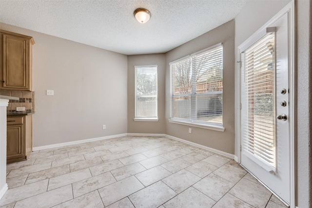 unfurnished dining area with light tile patterned floors and a textured ceiling