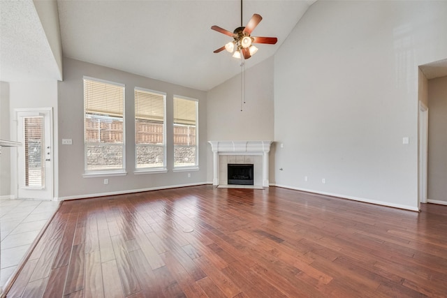 unfurnished living room with hardwood / wood-style flooring, a fireplace, high vaulted ceiling, and ceiling fan