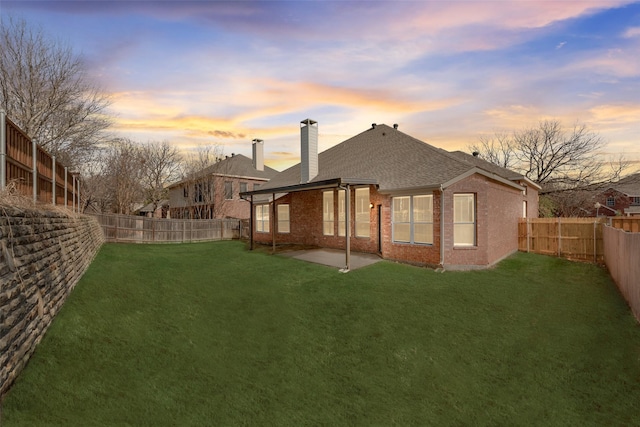 back house at dusk featuring a yard and a patio