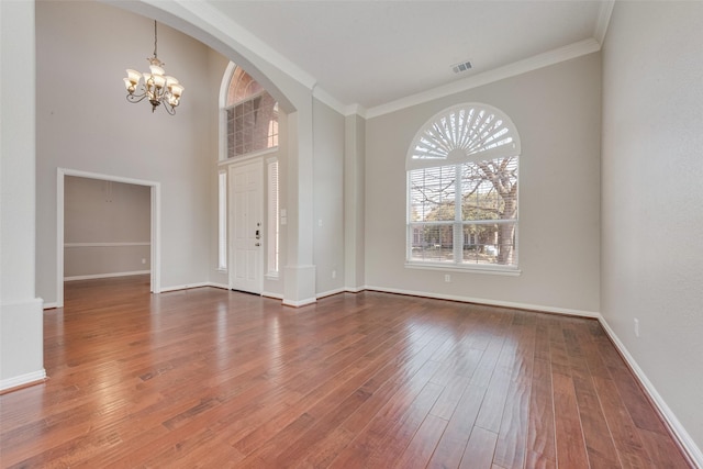 unfurnished room with hardwood / wood-style floors, ornamental molding, and a chandelier