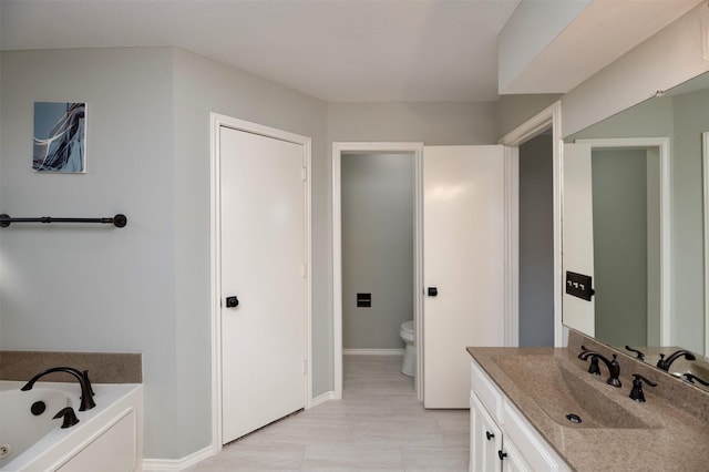 bathroom featuring vanity, a bath, and toilet