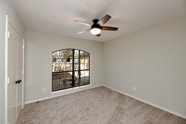 carpeted spare room featuring ceiling fan