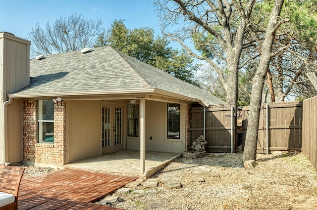 rear view of house with a wooden deck, a patio area, and french doors