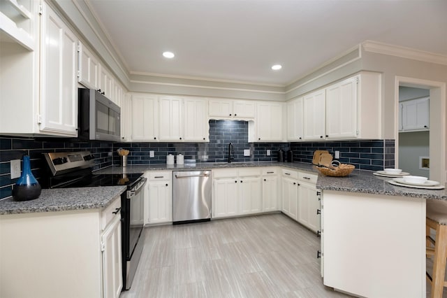 kitchen with stone counters, appliances with stainless steel finishes, a breakfast bar area, white cabinets, and kitchen peninsula