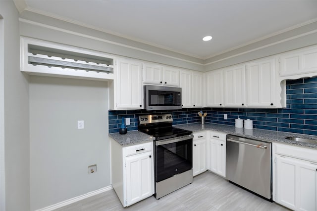 kitchen featuring light stone countertops, backsplash, stainless steel appliances, and white cabinets