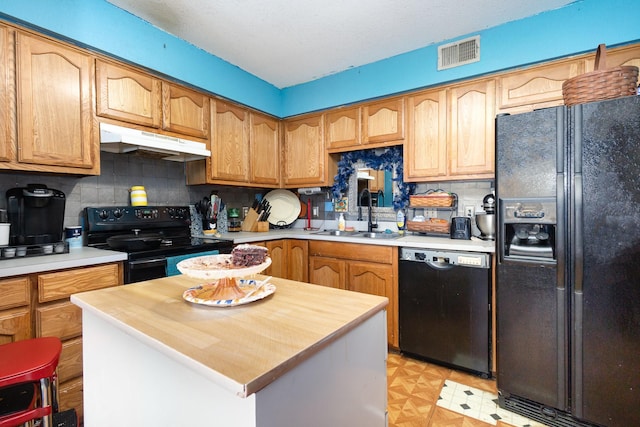 kitchen with under cabinet range hood, a sink, visible vents, light countertops, and black appliances