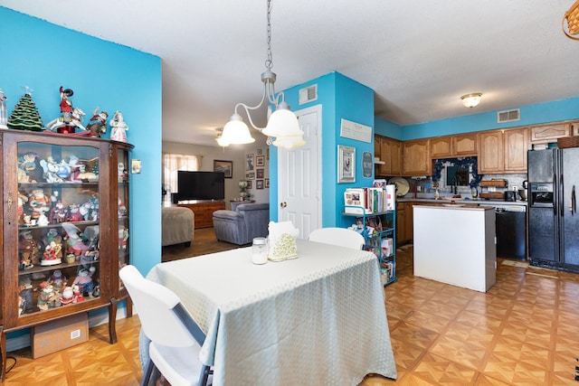 kitchen with visible vents, dishwasher, a center island, black refrigerator with ice dispenser, and pendant lighting