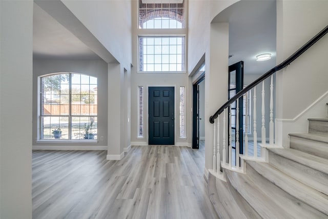 entryway with a towering ceiling and light hardwood / wood-style flooring