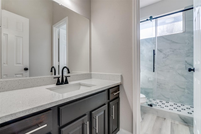 bathroom featuring a shower with door, vanity, wood-type flooring, and toilet