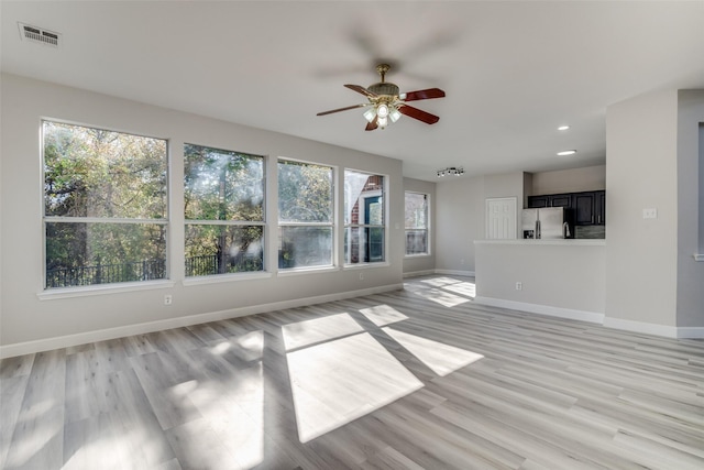 unfurnished living room with ceiling fan, a healthy amount of sunlight, and light wood-type flooring