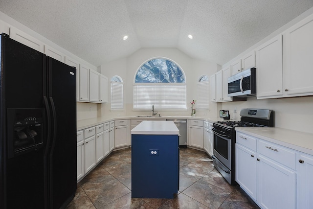 kitchen featuring a center island, stainless steel appliances, lofted ceiling, light countertops, and a sink