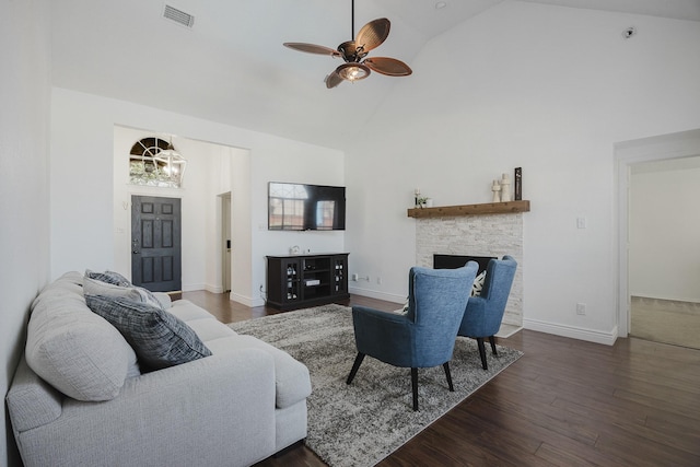 living area with baseboards, visible vents, wood finished floors, a fireplace, and high vaulted ceiling