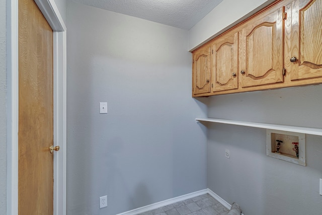 washroom with cabinets, hookup for a washing machine, and a textured ceiling