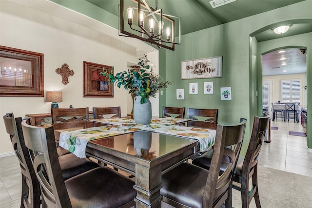 dining area featuring light tile patterned floors, baseboards, arched walkways, and an inviting chandelier