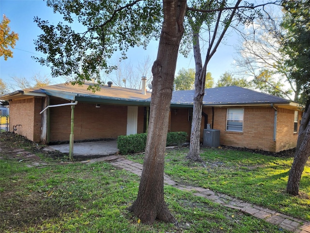 back of property featuring cooling unit and a yard