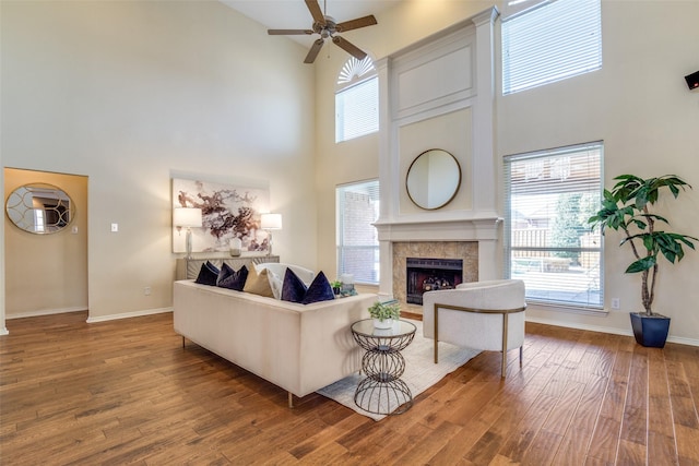 living area with a tiled fireplace, wood finished floors, and baseboards