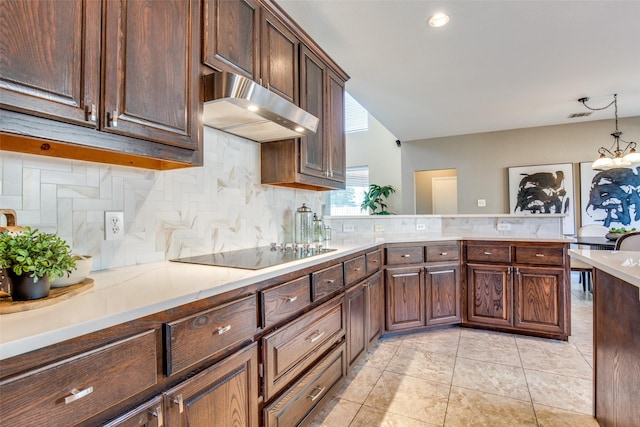 kitchen featuring tasteful backsplash, black electric stovetop, light countertops, under cabinet range hood, and pendant lighting