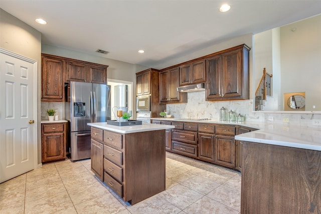 kitchen with under cabinet range hood, a kitchen island, visible vents, light countertops, and appliances with stainless steel finishes