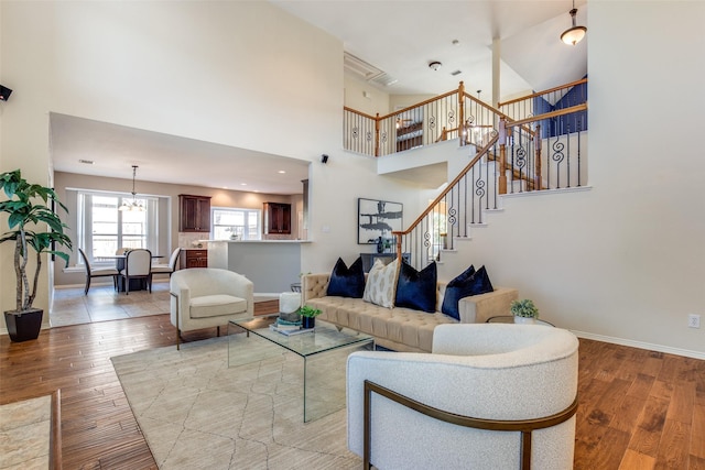 living room with a towering ceiling, baseboards, stairway, and light wood finished floors