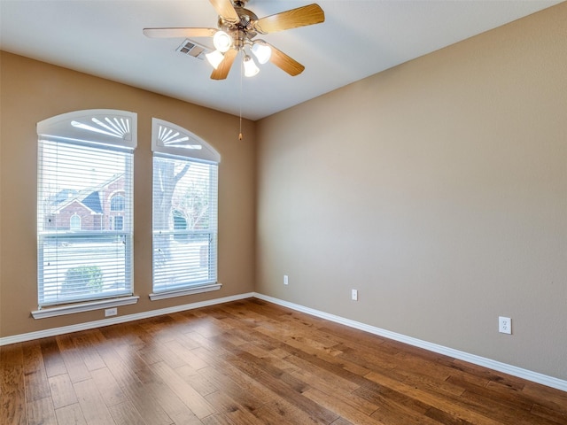 empty room featuring visible vents, ceiling fan, baseboards, and wood finished floors