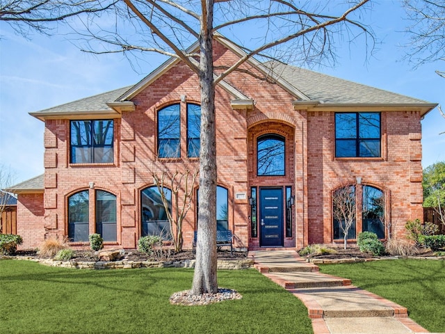 view of front of property featuring brick siding, a front lawn, and a shingled roof