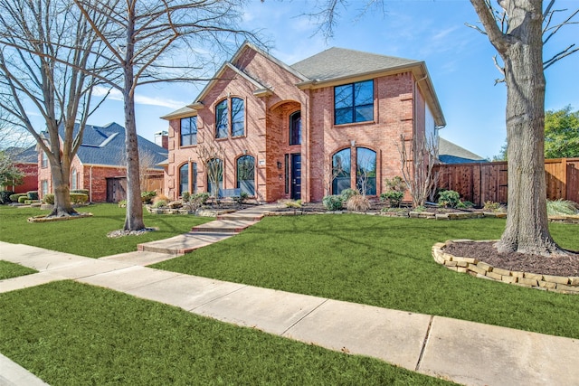 view of front facade featuring brick siding, a front yard, fence, and a shingled roof