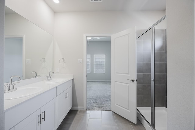 bathroom with double vanity, a shower stall, and a sink