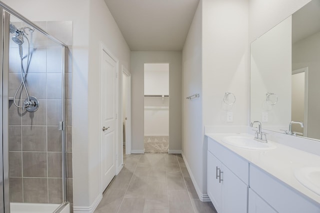 full bathroom featuring a sink, a shower stall, tile patterned flooring, double vanity, and baseboards