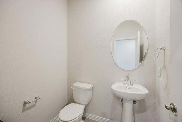 half bathroom with toilet and baseboards