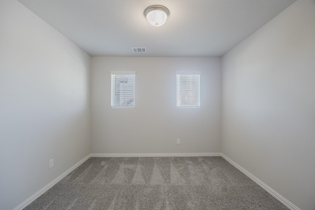 spare room featuring visible vents, baseboards, and carpet flooring