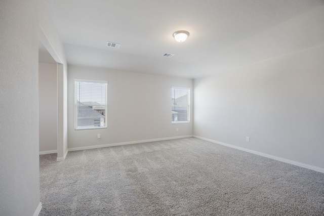 carpeted empty room with a healthy amount of sunlight, visible vents, and baseboards