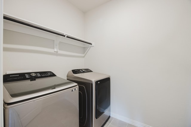 laundry area featuring washer and dryer, laundry area, baseboards, and tile patterned flooring