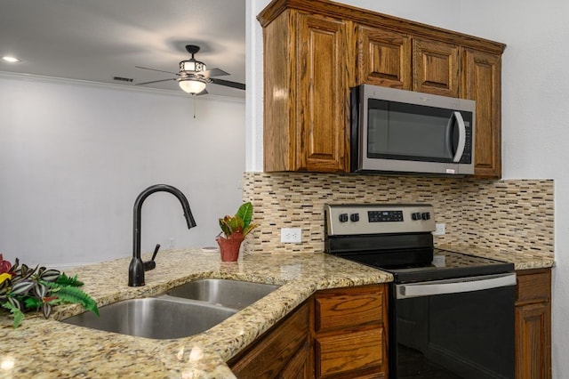 kitchen with crown molding, appliances with stainless steel finishes, sink, and light stone counters