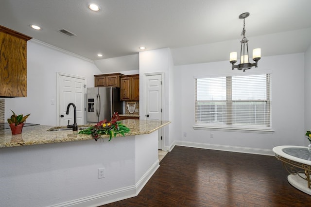 kitchen with stainless steel fridge with ice dispenser, decorative light fixtures, sink, kitchen peninsula, and light stone countertops