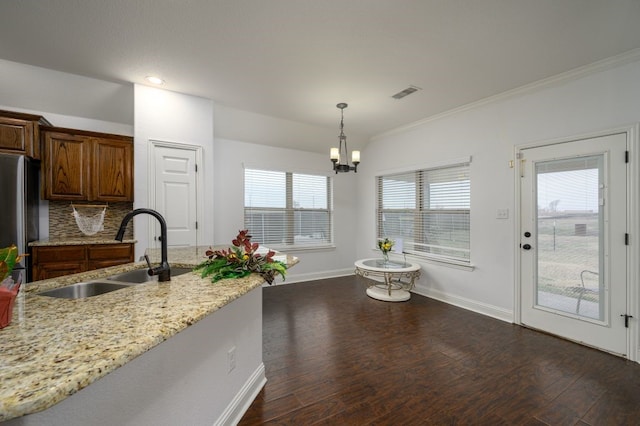 kitchen with pendant lighting, sink, stainless steel refrigerator, dark hardwood / wood-style floors, and light stone counters