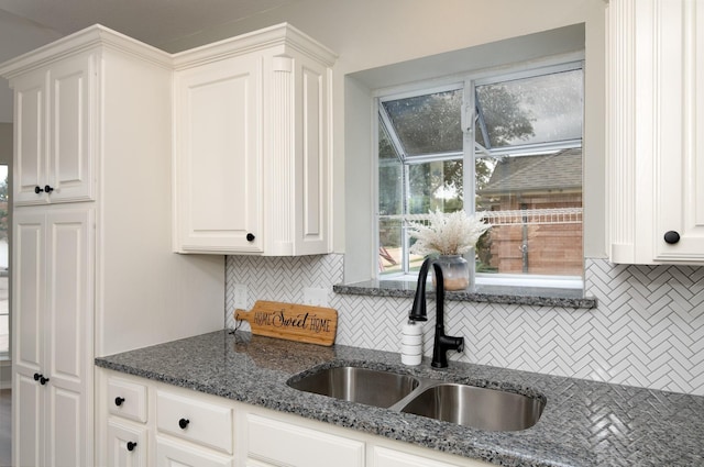 kitchen featuring white cabinetry, sink, decorative backsplash, and dark stone countertops