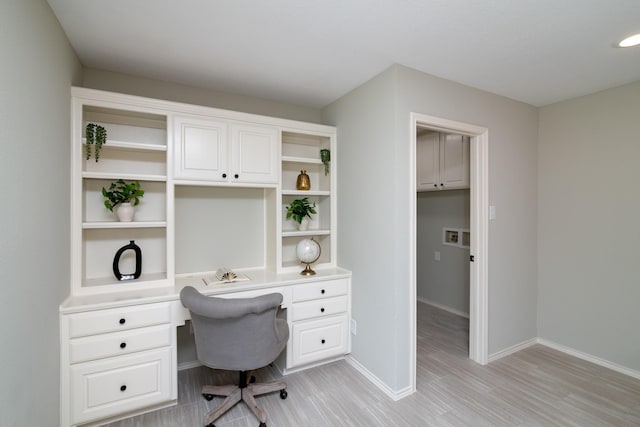 home office featuring built in desk and light hardwood / wood-style floors