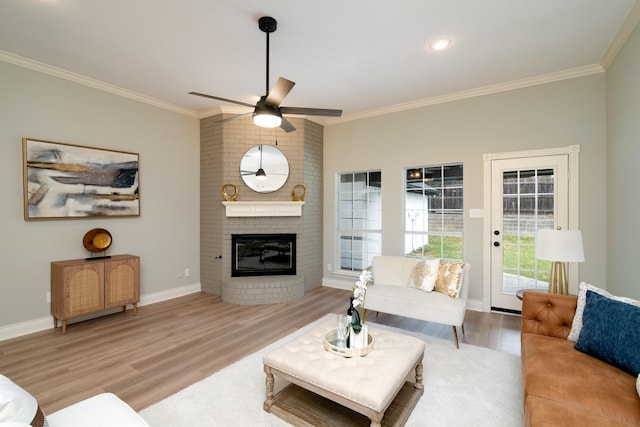 living room with a fireplace, light hardwood / wood-style flooring, ornamental molding, and ceiling fan