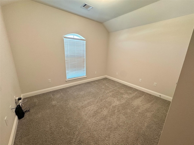 carpeted spare room featuring vaulted ceiling