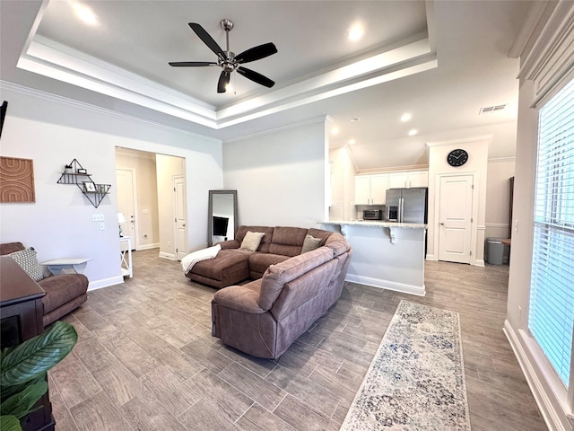 living room featuring hardwood / wood-style flooring, crown molding, and a raised ceiling