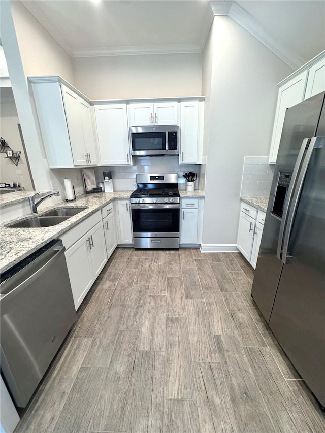 kitchen with light stone counters, appliances with stainless steel finishes, sink, and white cabinets