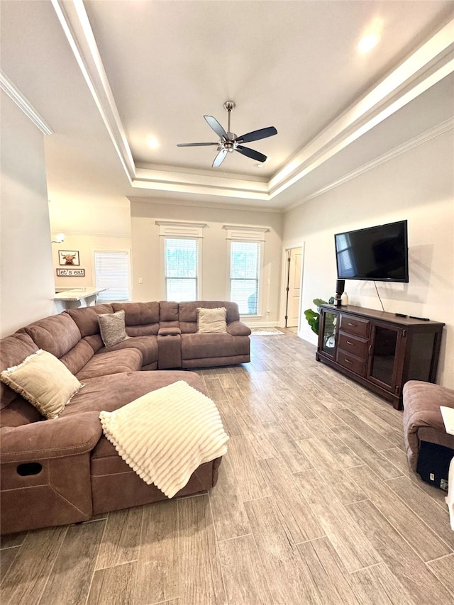 living room with ceiling fan, ornamental molding, and a raised ceiling