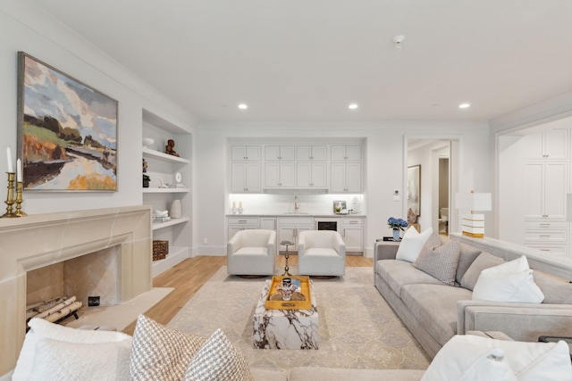 living room with wet bar, a high end fireplace, light hardwood / wood-style flooring, and built in features