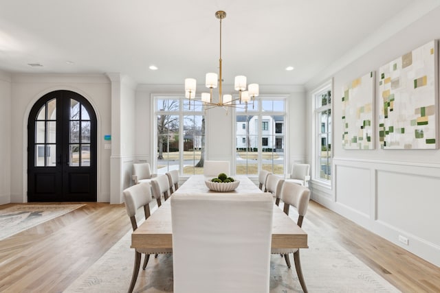 dining room featuring french doors, ornamental molding, an inviting chandelier, and light hardwood / wood-style flooring