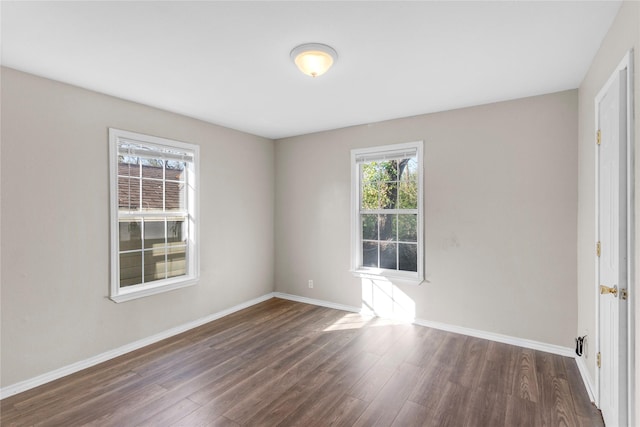 empty room featuring a healthy amount of sunlight and dark wood-type flooring